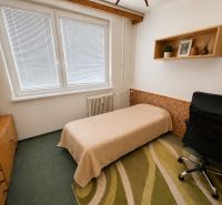 Bedroom in a 3-room apartment with a bed, an office chair, and a shelf on the wall.