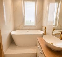 Bathroom with a bathtub and a sink in a 3-room apartment, light marble decor.