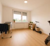 A room in a 3-room apartment with a wooden decor floor, a drying rack, and scooters.