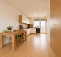 A kitchen in a 3-room apartment with a dining table and a floor with a wooden decor.