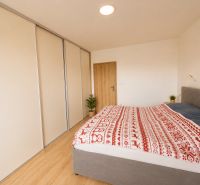 Bedroom with wood-patterned flooring in a 3-room apartment with a built-in wardrobe.
