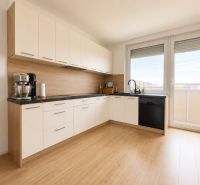 A kitchen in a 3-room apartment with a wooden decor floor and access to a balcony.