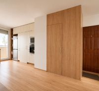 A kitchen in a 3-room apartment with a wooden decor floor and built-in appliances.
