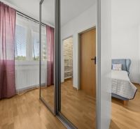 Interior of a 3-room apartment with a wooden decor floor, mirrored wardrobe, and curtains.