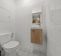 A toilet with white tiles and a sink with a wooden decor in a 3-room apartment.