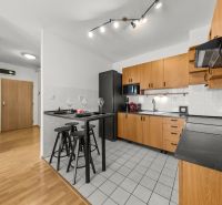 A kitchen in a 3-room apartment with light furniture and a wooden decor floor.