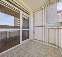 Glazed loggia with a view from a 3-room apartment, tiles, light wall.