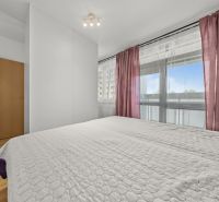 A bright bedroom with pink curtains and a wood-patterned floor in a three-room apartment.