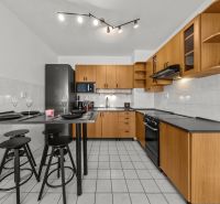 A kitchen in a 3-room apartment with wooden decor, a bar counter, and minimalist equipment.