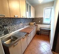 A kitchen of a three-room apartment with mosaic tiles and a wooden decor floor.