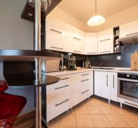 A kitchen with white cabinets in a two-room apartment and a floor with a wood decor.