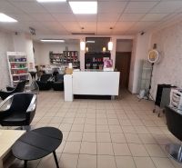 Interior of commercial premises with hairdressing equipment, sofas, and shelves with products.