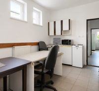 Interior of a warehouse and hall with an office, table, chairs, and kitchen appliances.