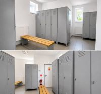 A locker room with gray lockers and wooden benches suitable for warehouses and halls.