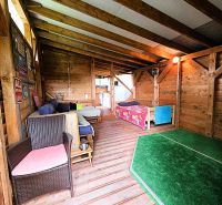 Wooden cabin with comfortable seating and a children's bed on the floor with a wooden decor.