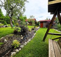 A garden with a swing near a cottage in Košice - the Západ district, surrounded by greenery and trees.