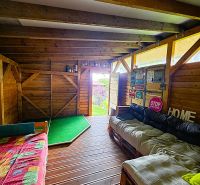 Interior of a cabin with a wooden decor floor, pallet sofas, and decorative boards.