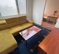 Living room in a three-room apartment with a wooden decor floor and a yellow sofa.