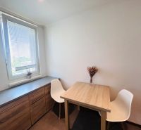 Dining room in a 3-room apartment with a wooden table, chairs, and a sideboard.
