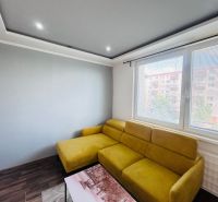 A bright living room with a comfortable yellow sofa and a wooden decor floor.