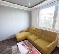 Living room with a mustard sofa, coffee table, and wooden decor flooring.
