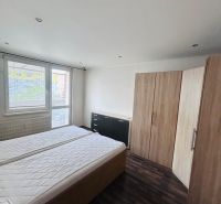 A bedroom in a three-room apartment with a wooden decor floor and furniture.