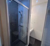 A bathroom in a three-room apartment with a shower and white tiles.