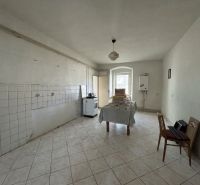 White kitchen in a family house with simple furnishings and tiled floor.