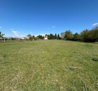 A green plot of land in Čifáre surrounded by fencing and trees, ideal for a family house.