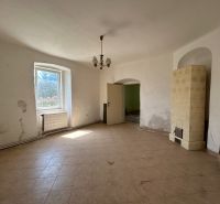 Interior of a family house with a window, white walls, and a traditional tiled stove.