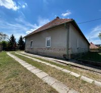 A family house in Čifáre with a lawn and a paved walkway next to a stone fence.