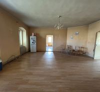 Interior of a family house with a wooden decor floor, older furniture, and a refrigerator.