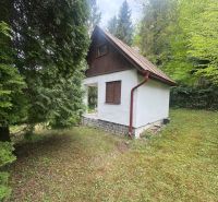 A cottage in Svinica surrounded by nature, white exterior with a brown roof.