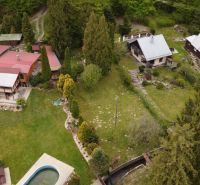An aerial view of cottages in Nižný Klátov with surrounding greenery and a swimming pool.