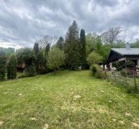 A garden with a cottage in Svinica, surrounded by trees and landscaped greenery.