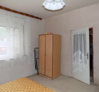 A room with simple furniture, curtains on the window, and a carpet on the floor in a family house.