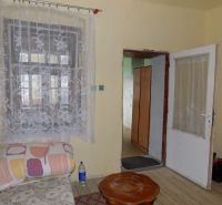 A room in a family house with curtains on the window and a floor with a wooden decor.