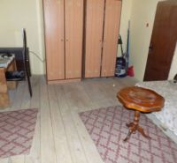 A room in a family house with wooden decor, carpet, furniture, and a table.