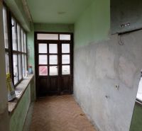 A hallway in a family house with large windows, a floor with a wooden decor.