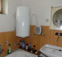 A bathroom in a family house with an electric boiler and a sink.