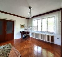 Living room in a family house with wood-patterned flooring and a large window.