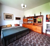 In the family house, there is a room with a bed, a wooden wardrobe, and a carpet.