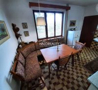 The kitchen in the family house has wooden furniture and a tiled floor.