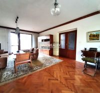 Living room of a family house with a wooden decor floor, comfortable seating, and a writing desk.