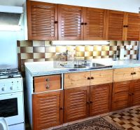 A kitchen in a family house with wooden cabinets and a stove, floor with wooden decor.