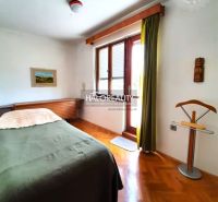 A bedroom in a family house with a bed, a painting, and a wooden decor floor.