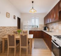 A kitchen in a family house with a wooden decor floor, a dining table, and a kitchen unit.