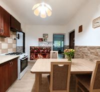A kitchen in a family house with a kitchen unit, a dining table, and a floor with a wooden decor.