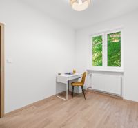 A room in a 3-room apartment with a desk, chair, and a wooden decor floor.