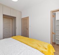 A bedroom in a 3-room apartment with a wooden decor floor and a spacious wardrobe.